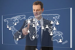 Ein Geschäftsmann steht vor einer digitalen Weltkarte 