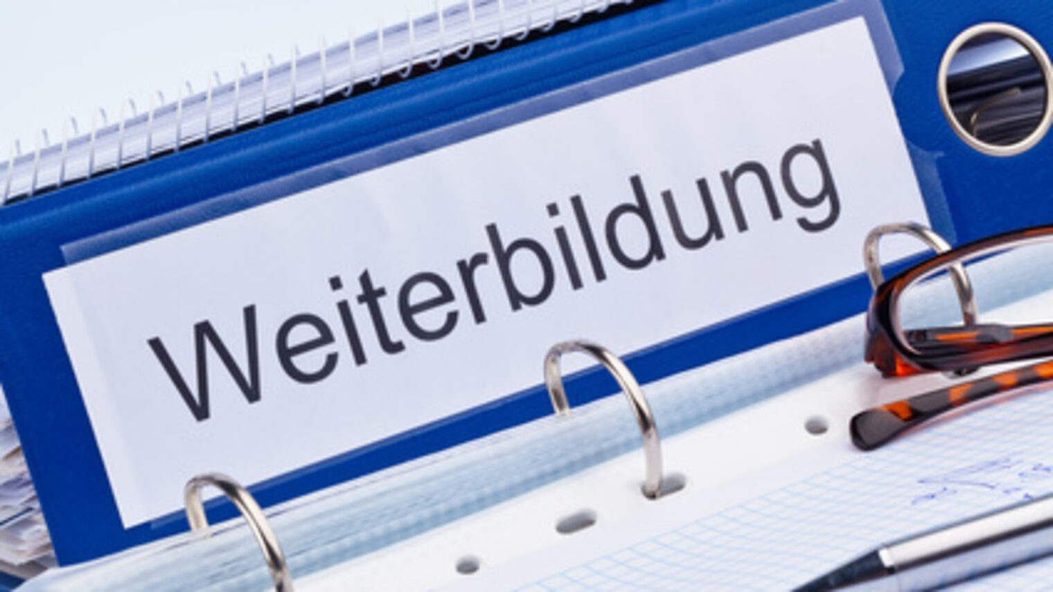 blauer Ordner mit der Aufschrift Weiterbildung