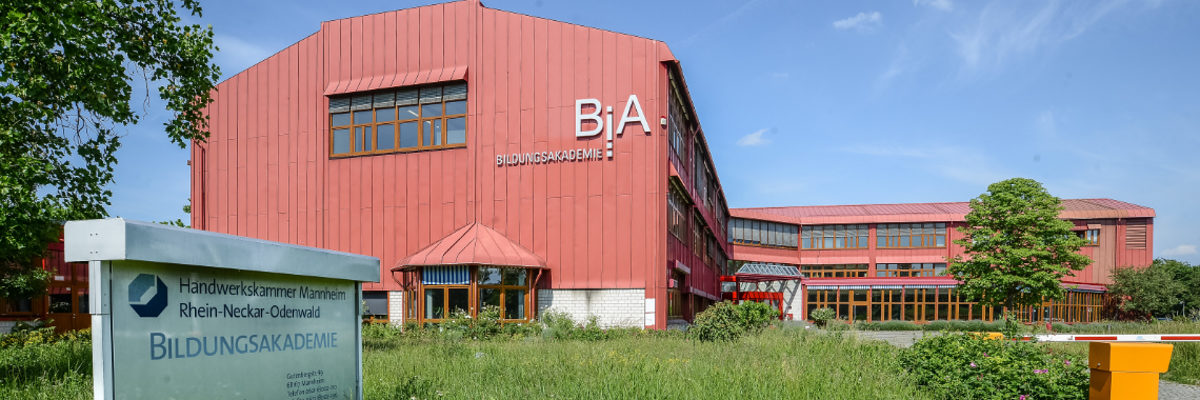 Die Bildungsakademie in Mannheim-Wohlgelegen; Gebäude mit viel Glas-Einsatz und die Fassade in rot gehalten. 