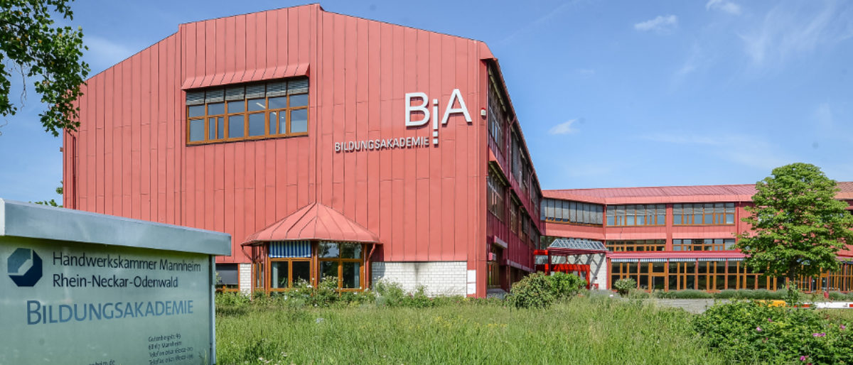 Die Bildungsakademie in Mannheim-Wohlgelegen; Gebäude mit viel Glas-Einsatz und die Fassade in rot gehalten. 