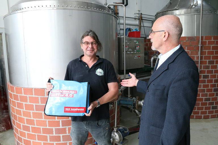 Inhaber Kai Müller der Lobdengau-Brauerei Müller mit dem Werkzeugkoffer, überreicht von Detlev Michalke, Leiter der Pressestelle der Handwerkskammer