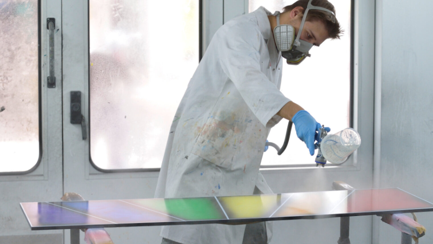 Maler- und Lackierer arbeitet in der Sprühkabine und besprüht eine Fläche mit der Sprühpistole