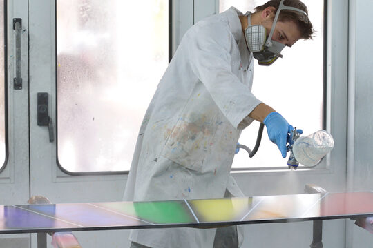Maler- und Lackierer arbeitet in der Sprühkabine und besprüht eine Fläche mit der Sprühpistole