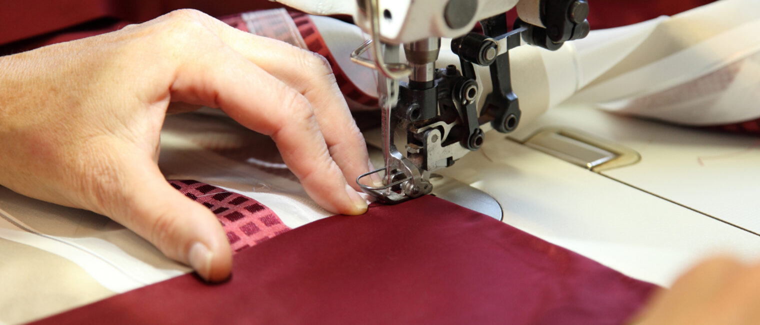 Raumausstatter - Stoffarbeiten Händer beim Nähen an der Nähmaschine.