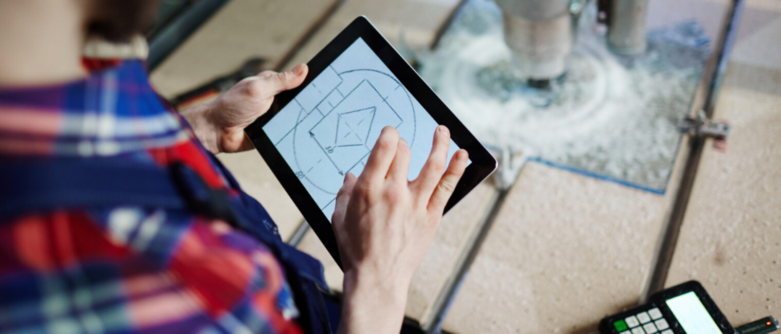 Jugendlicher hat ein Tablet in der Hand, auf dem eine geometrische Zeichnung abgebildet ist.