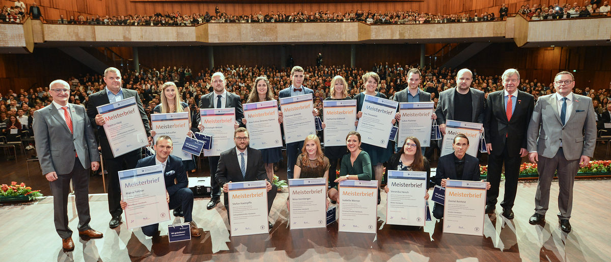 © Thomas Rittelmann | Die besten Meisterinnen und Meister aus den 16 geprüften Berufen stellten sich in der Feierstunde zusammen mit Präsident Klaus Hofmann (rechts), Vizepräsident Martin Sättele (2.v.r.) und Vizepräsident Steffen Haug (links) dem Fotografen. Meisterfeier 2019, Gruppenbild