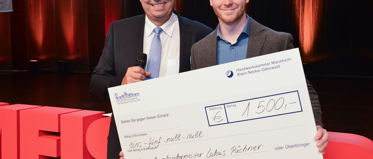 © Thomas Rittelmann | Michael Schillinger (links), Vorstandsvorsitzender der Inter-Versicherungsgruppe, bei der Übergabe des Schecks an den besten Meister aus einem innovativen Handwerk, Feinwerkmechanikermeister Lukas Püchner (rechts). Meisterfeier 2019, Innovationspreis, Feinwerkmechaniker, Handwerk