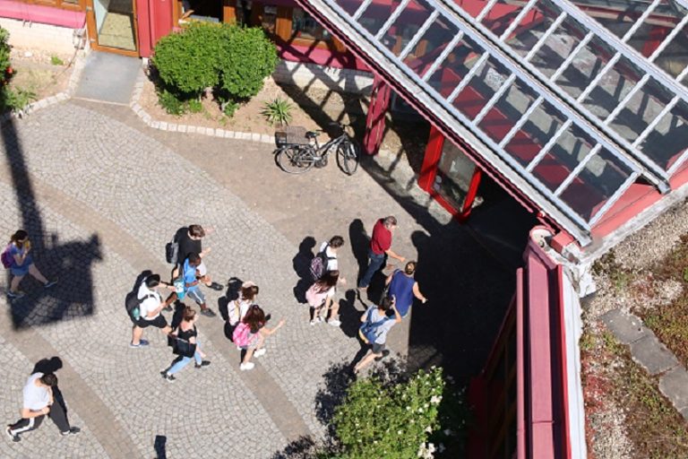Luftansicht des Eingangs der Bildungsakademie Mannheim während Schüler das Gebäude betreten.