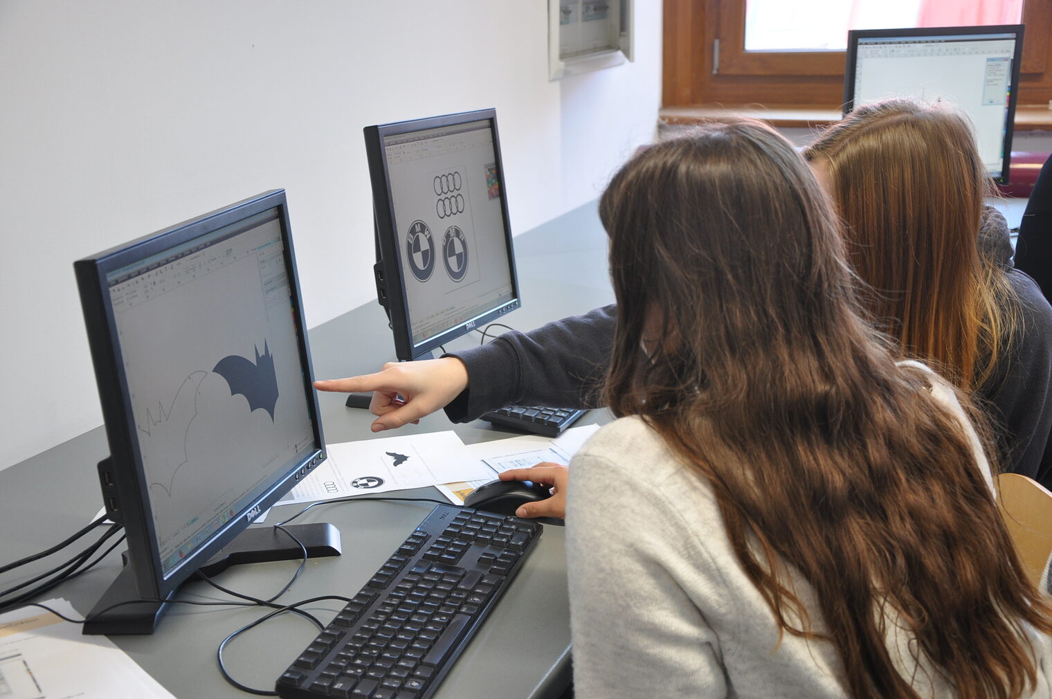 Schülerinnen bei der Logogestaltung am Computer. 