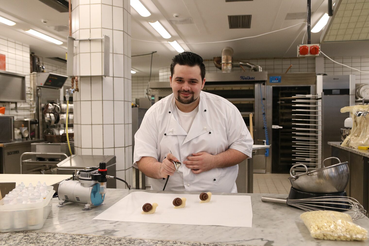 Meister im Bäcker- und Konditoren-Handwerk stellt kleine Süßteilchen her. 