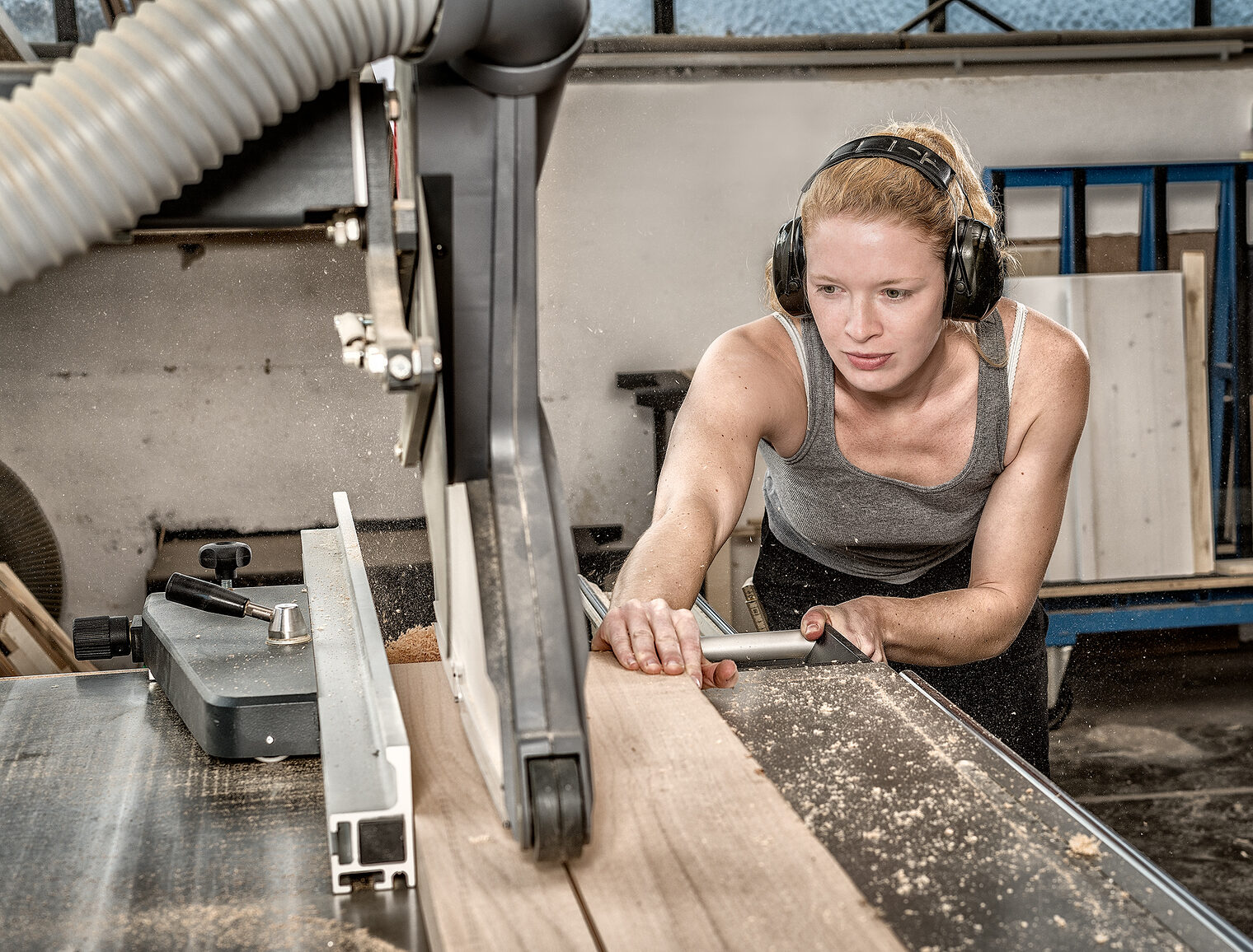 Eine Frau schneidet an einer Maschine ein stück Holz 