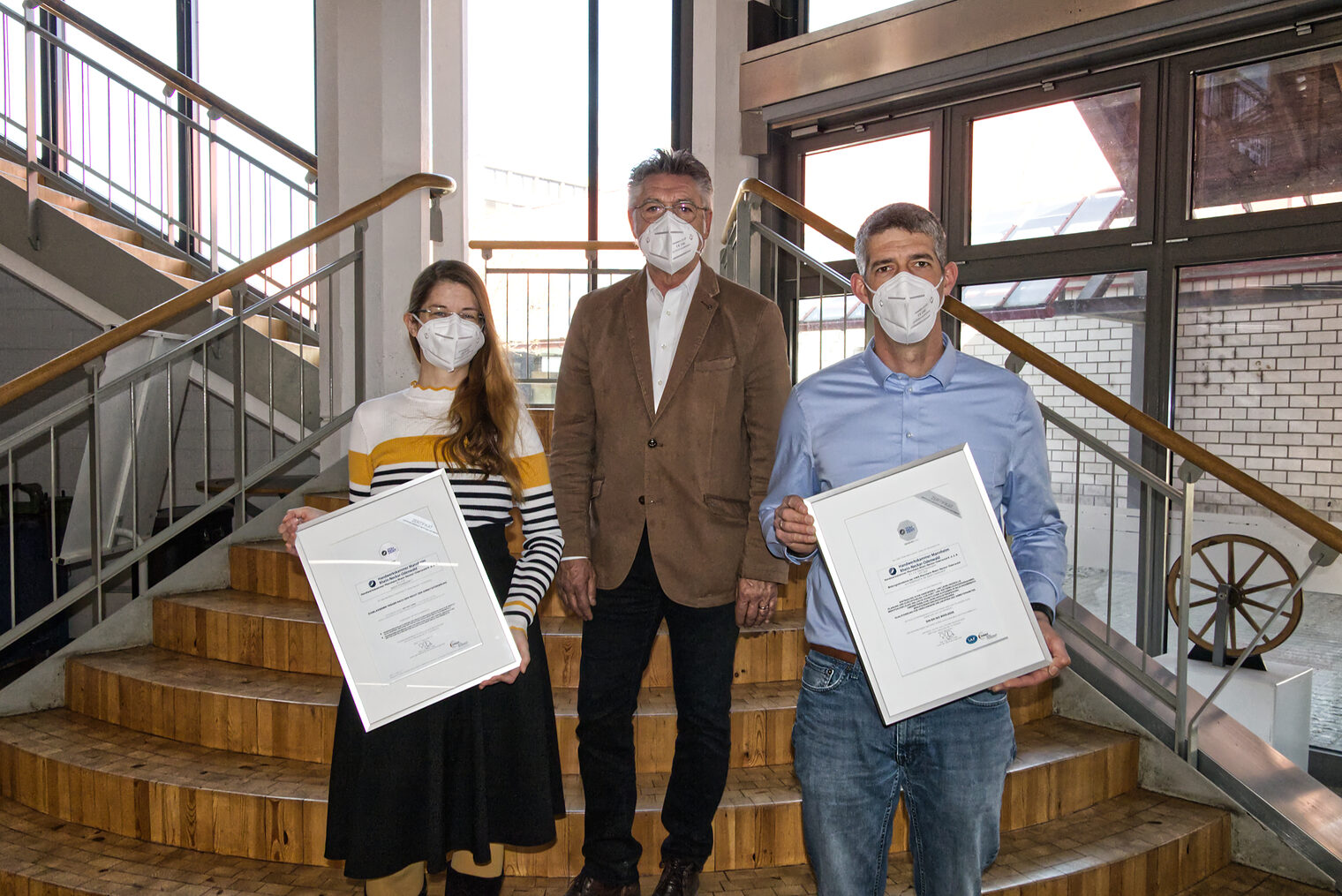 Mitarbeiter der Handwerkskammer im Treppenhaus der Bildungsakademie in Mannheim mit neu erhaltenem DIN EN ISO 9001 Zertifikat.