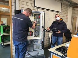 Florian Kuolt arbeitet in einer Elektrowerkstattt mit einem Ausbilder an einer Schaltwand