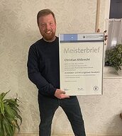 Person mit Meisterbrief in der Hand