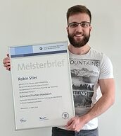 Person mit Meisterbrief in der Hand