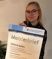 Person mit Meisterbrief in der Hand