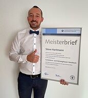 Person mit Meisterbrief in der Hand