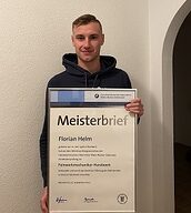 Person mit Meisterbrief in der Hand