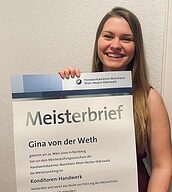 Person mit Meisterbrief in der Hand