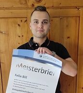 Person mit Meisterbrief in der Hand