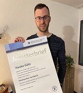 Person mit Meisterbrief in der Hand