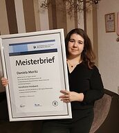 Person mit Meisterbrief in der Hand