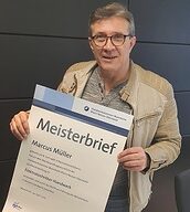 Person mit Meisterbrief in der Hand