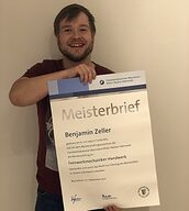 Person mit Meisterbrief in der Hand