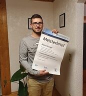 Person mit Meisterbrief in der Hand