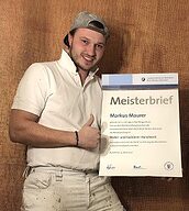 Person mit Meisterbrief in der Hand