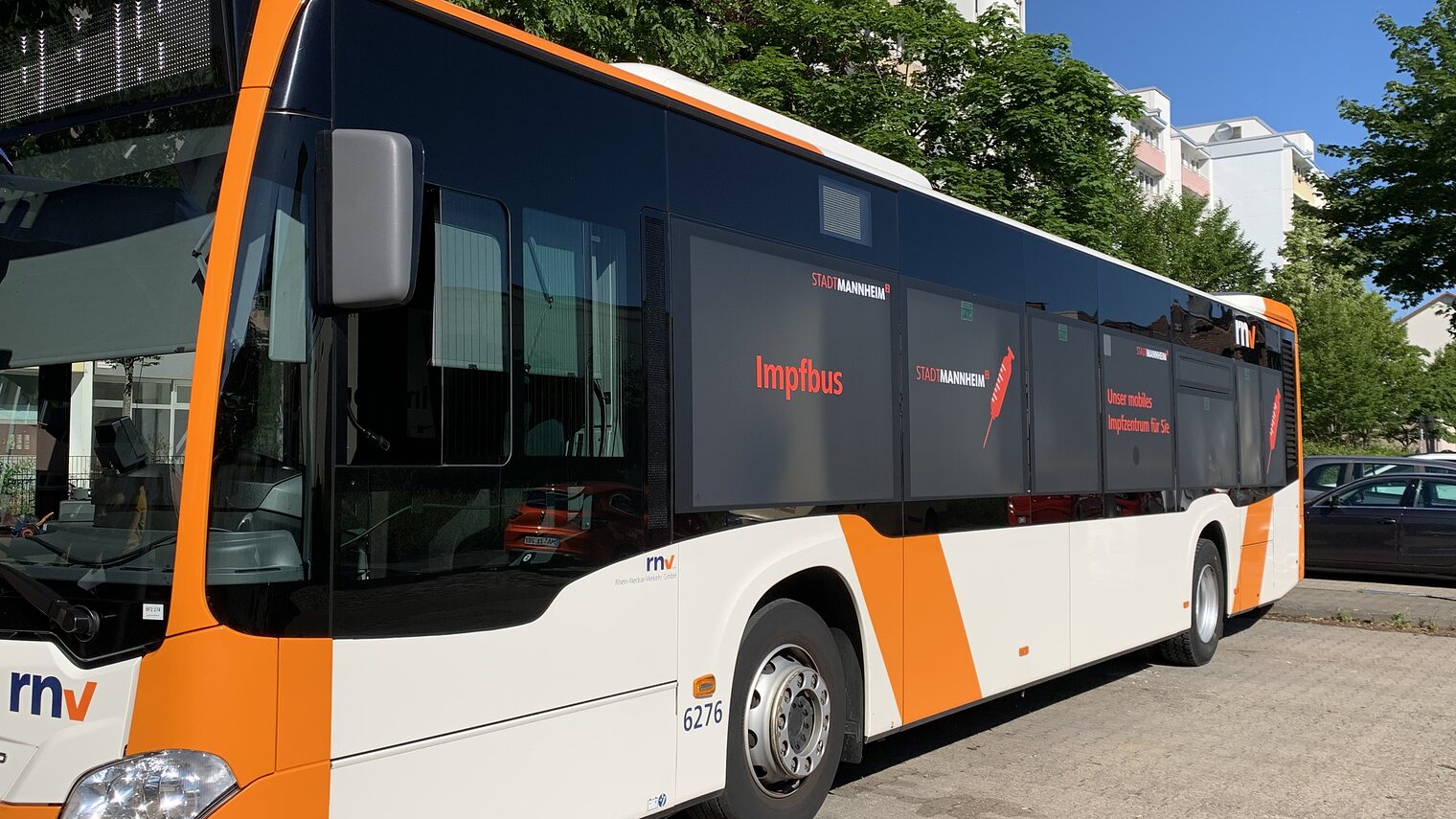 Bus in den Farben orange und weiß, Logo rnv und Aufschrift Impfbus auf den Fenstern 