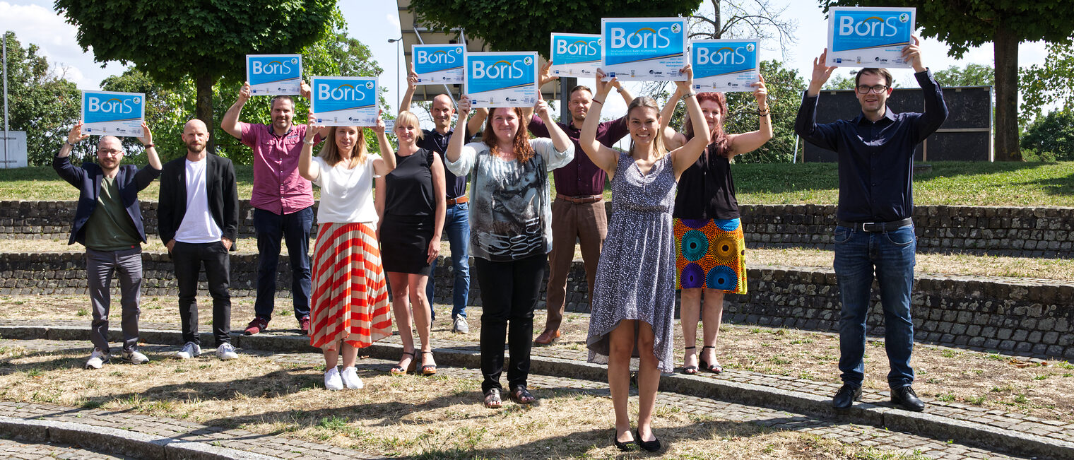 11 Projektverantwortliche der ausgezeichneten Schulen stellten sich zu einem Gruppenfoto auf, bei dem sie das überreichte BoriS-Schild in die Höhe streckten.