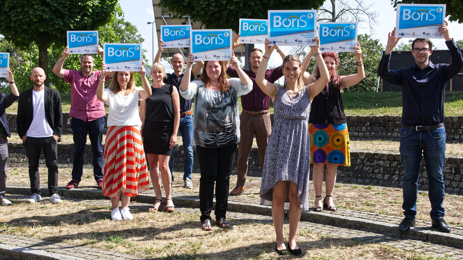 11 Projektverantwortliche der ausgezeichneten Schulen stellten sich zu einem Gruppenfoto auf, bei dem sie das überreichte BoriS-Schild in die Höhe streckten.