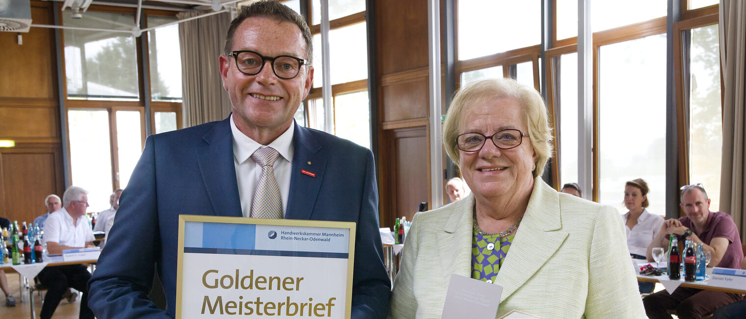 Ehrenkreishandwerksmeisterin Margot Preisz mit Präsident Klaus Hofmann, der den Goldenen Meisterbrief in den Händen hält.