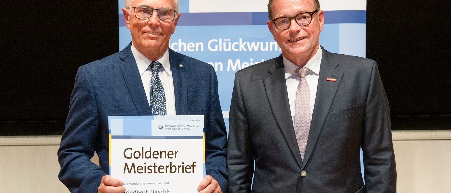 Kammerpr&auml;sident Klaus Hofmann &uuml;berreicht Tischlermeister Friedbert Blaschke auf der Goldene Meisterfeier in Wiesloch 2022 seinen Goldenen Meisterbrief