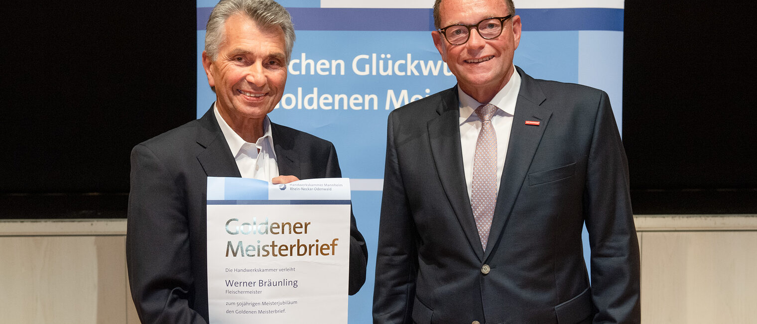 Kammerpr&auml;sident Klaus Hofmann &uuml;berreicht Fleischermeister Werner Br&auml;unling auf der Goldene Meisterfeier in Wiesloch 2022 seinen Goldenen Meisterbrief