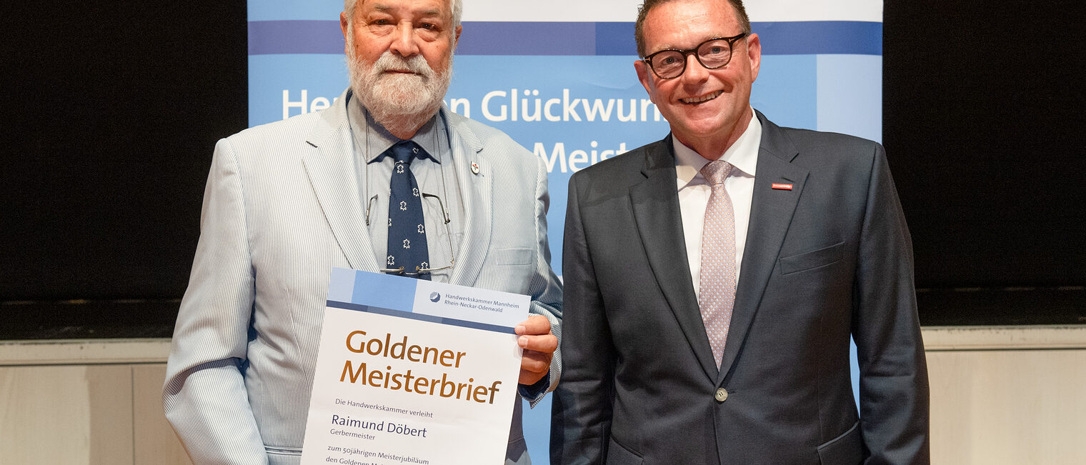 Kammerpr&auml;sident Klaus Hofmann &uuml;berreicht Gerbermeister Raimund D&ouml;bert auf der Goldene Meisterfeier in Wiesloch 2022 seinen Goldenen Meisterbrief