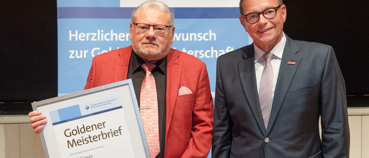 Kammerpräsident Klaus Hofmann überreicht Fleischermeister Rolf Gieser auf der Goldene Meisterfeier in Wiesloch 2022 seinen Goldenen Meisterbrief