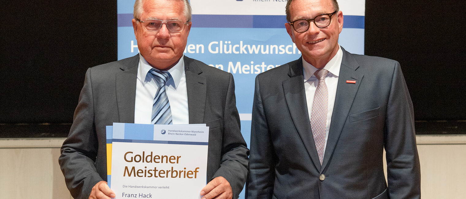 Kammerpräsident Klaus Hofmann überreicht Maler- und Lackierermeister Franz Hack auf der Goldene Meisterfeier in Wiesloch 2022 seinen Goldenen Meisterbrief