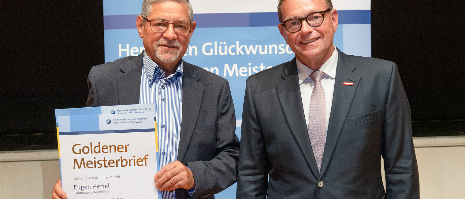 Kammerpr&auml;sident Klaus Hofmann &uuml;berreicht Raumausstattermeister Eugen Hertel auf der Goldene Meisterfeier in Wiesloch 2022 seinen Goldenen Meisterbrief