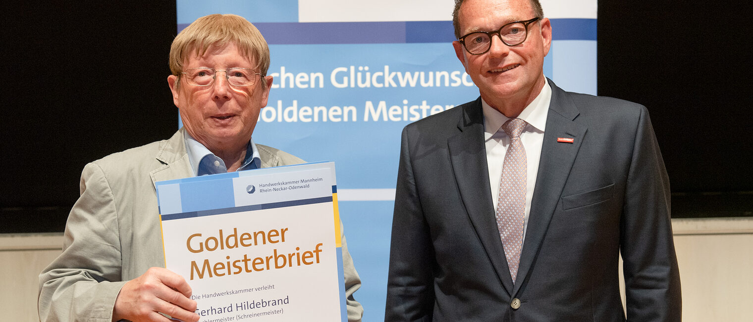 Kammerpräsident Klaus Hofmann überreicht Tischlermeister Gerhard Hildebrand auf der Goldene Meisterfeier in Wiesloch 2022 seinen Goldenen Meisterbrief