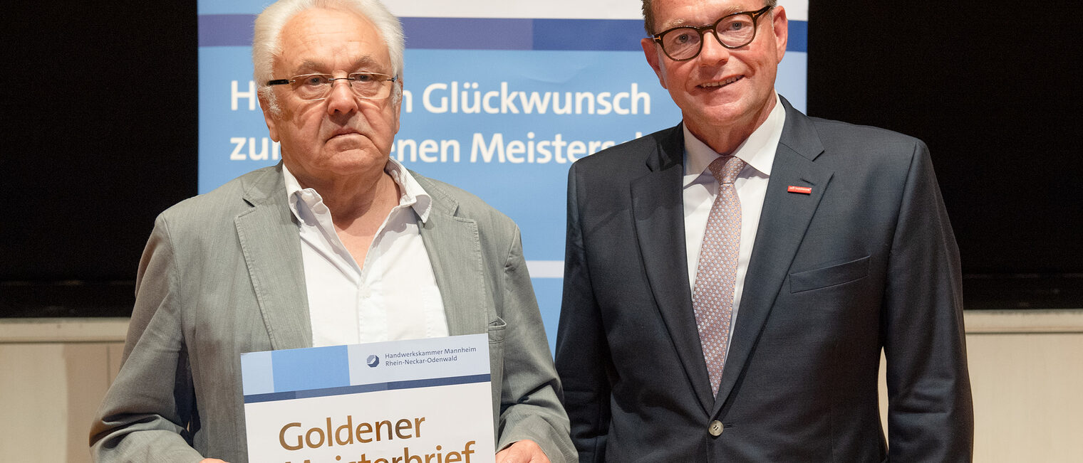 Kammerpräsident Klaus Hofmann überreicht Kraftfahrzeugtechnikermeister Edmund Hör auf der Goldene Meisterfeier in Wiesloch 2022 seinen Goldenen Meisterbrief