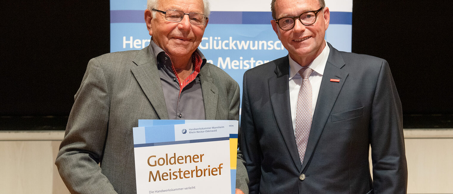 Kammerpräsident Klaus Hofmann überreicht Feinmechanikermeister Bernd Jenne auf der Goldene Meisterfeier in Wiesloch 2022 seinen Goldenen Meisterbrief