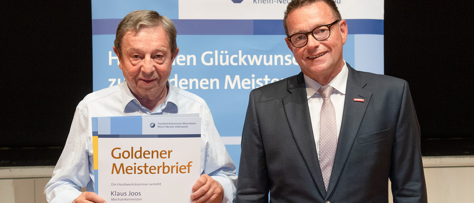 Kammerpräsident Klaus Hofmann überreicht Mechanikermeister Klaus Joos auf der Goldene Meisterfeier in Wiesloch 2022 seinen Goldenen Meisterbrief