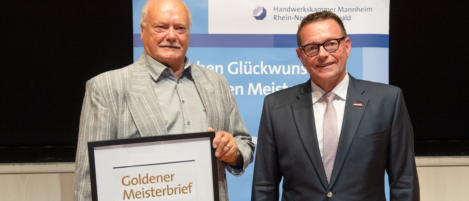 Kammerpr&auml;sident Klaus Hofmann &uuml;berreicht Maler- und Lackierermeister Karl Ke&szlig;ler auf der Goldene Meisterfeier in Wiesloch 2022 seinen Goldenen Meisterbrief