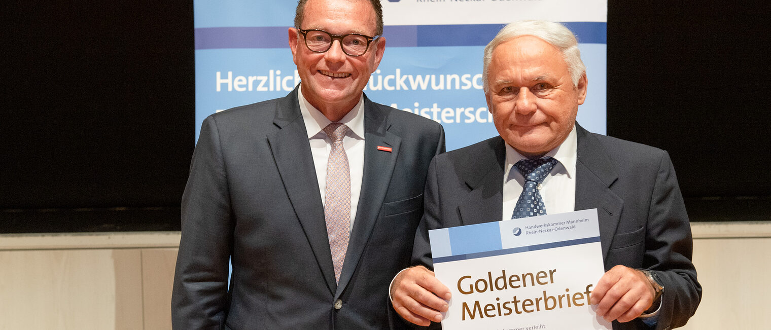 Kammerpräsident Klaus Hofmann überreicht Zentralheizungs- und Lüftungsbauermeister Karl-Otto Lintz auf der Goldene Meisterfeier in Wiesloch 2022 seinen Goldenen Meisterbrief