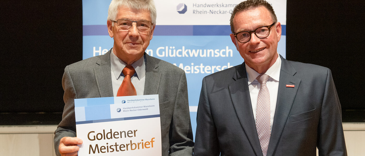 Kammerpr&auml;sident Klaus Hofmann &uuml;berreicht Feinmechanikermeister Volkker Mallinger auf der Goldene Meisterfeier in Wiesloch 2022 seinen Goldenen Meisterbrief