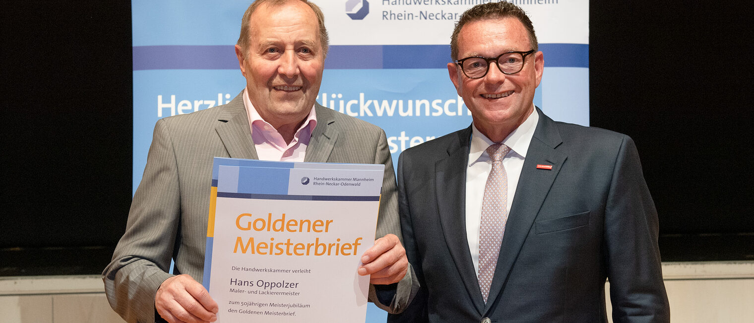 Kammerpräsident Klaus Hofmann überreicht Maler- und Lackierermeister Hans Oppolzer auf der Goldene Meisterfeier in Wiesloch 2022 seinen Goldenen Meisterbrief
