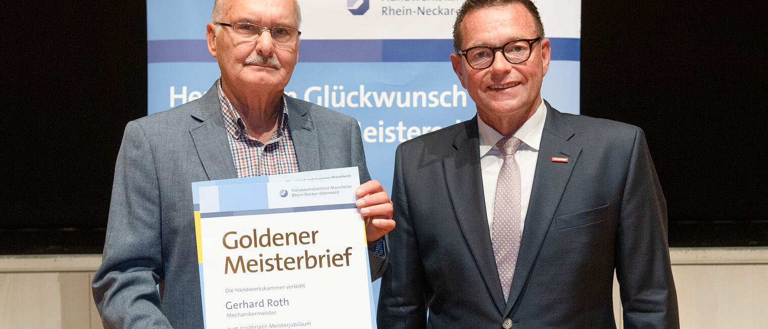 Kammerpr&auml;sident Klaus Hofmann &uuml;berreicht Mechanikermeister Gerhard Roth auf der Goldene Meisterfeier in Wiesloch 2022 seinen Goldenen Meisterbrief
