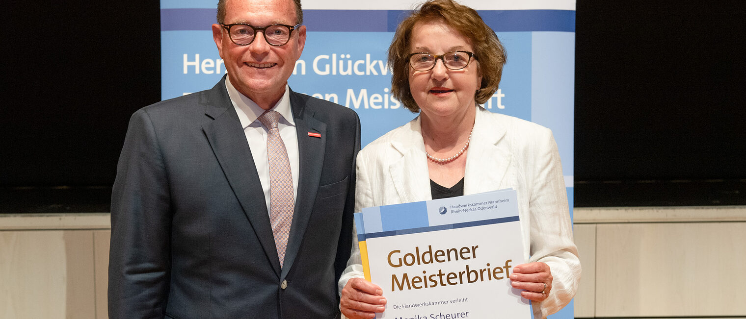 Kammerpr&auml;sident Klaus Hofmann &uuml;berreicht Friseurmeisterin Monika Scheurer auf der Goldene Meisterfeier in Wiesloch 2022 ihren Goldenen Meisterbrief